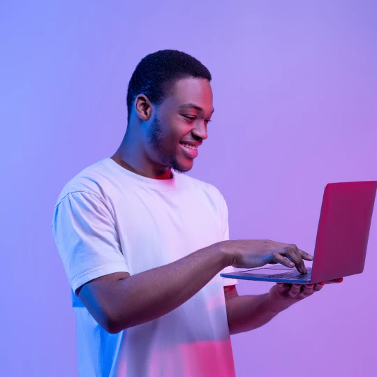Homme content qui regarde son ordinateur et qui suis une formation en ligne chez l'Aubaine formation